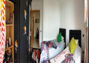 Ein Schlafzimmer mit einem bett, das Rennsport-Elemente aufweist, einem Holzschrank und einer Tür mit floralen Verzierungen.