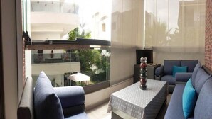 A modern living room with a sofa, a coffee table, and a view of a balcony. - Pleasant Apartment in Blanca Beach 4873 (Sidi Rahal)