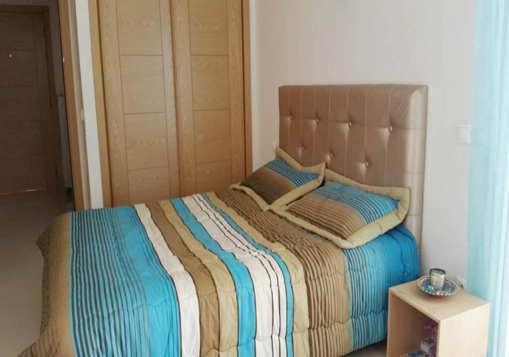 Ein Schlafzimmer mit einem Bett, einem Holzschrank und einem kleinen Nachttisch.