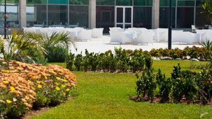 A modern building with large glass windows and a courtyard with white lounge chairs. - Pleasant apartment in Ola Blanca 4876 (Sidi Rahal)