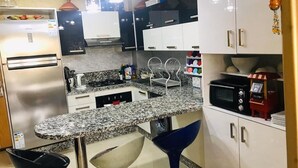 Una cocina moderna con encimeras de granito, electrodomésticos de acero inoxidable y armarios blancos.