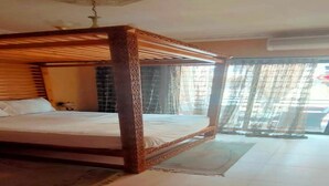 A four-poster bed with a wooden frame and a white mattress in a room with tiled flooring and a large window with curtains. - Residence Achraf Gueliz 4883 (Marrakech)