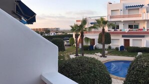 Ein Wohngebäude mit Schwimmbad, Palmen und einem Balkon.