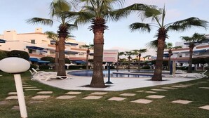 Ein Innenhof mit Palmen, einem Pool und Liegestühlen.