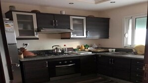 Eine moderne Küche mit dunklen Schränken, einem Gasherd, einem Backofen und einem Edelstahl-Kühlschrank.