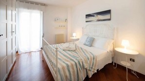 Un dormitorio con cama, lámparas de noche, un cuadro y vista al mar.