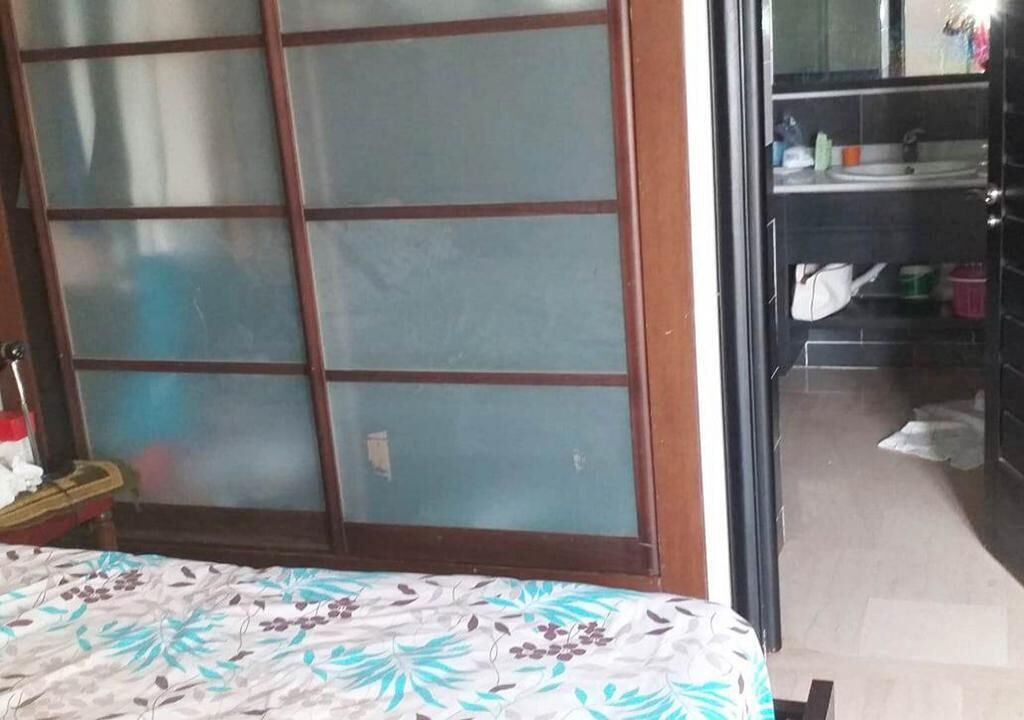 A room with a bed, a sliding glass door leading to a bathroom, and a small table with a chair.