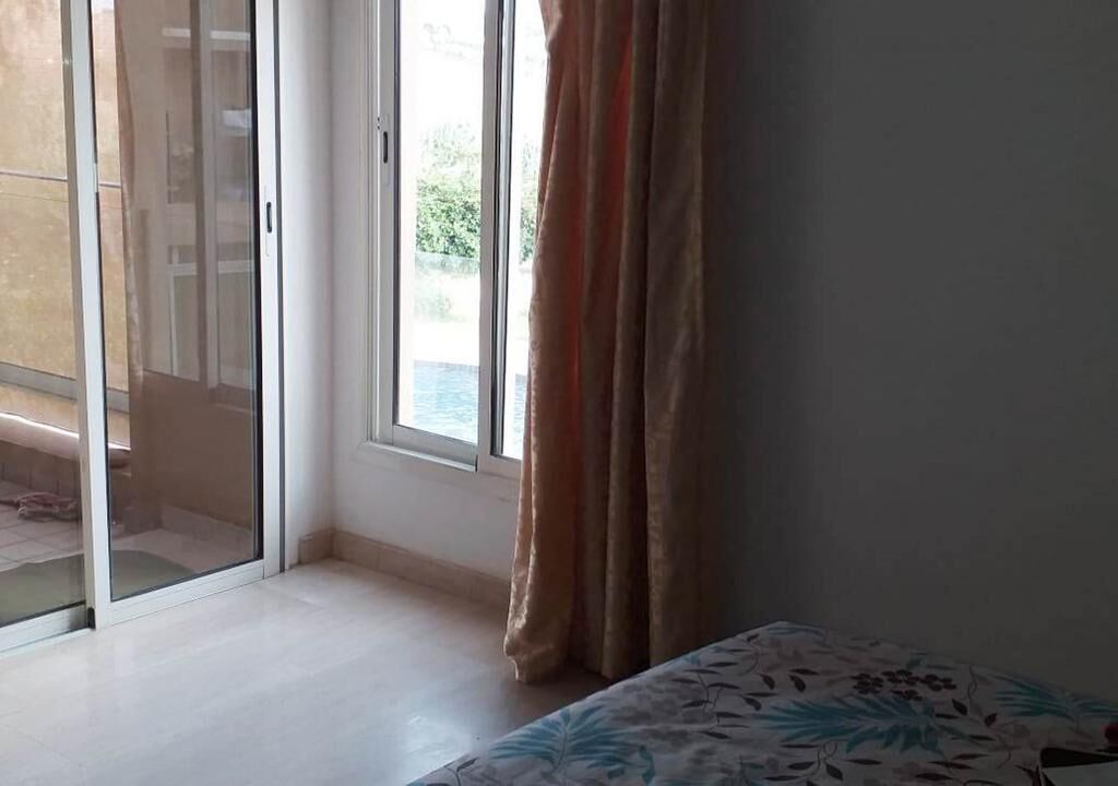 A room with a bed, a sliding glass door leading to an outdoor area, and a window with curtains.