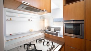 A modern kitchen with wooden cabinets, a gas stove, and a built-in oven. - WePuglia - Belvedere sul Porto (Monopoli)