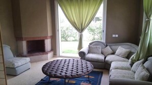 Un salon avec une cheminée, un canapé, une causeuse et un tapis à motifs.