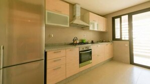 Une cuisine moderne dotée d’appareils électroménagers en acier inoxydable, de meubles en bois et d’une grande fenêtre qui laisse entrer la lumière naturelle.