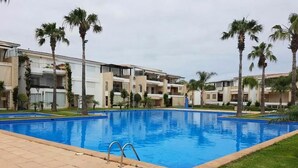 A swimming pool surrounded by palm trees and modern buildings.