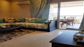 A living room with a sofa, coffee table, and a view of the balcony.