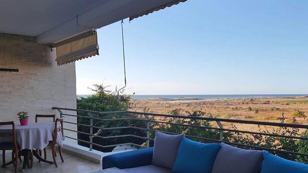 A balcony with a sofa and table, overlooking a desert landscape.