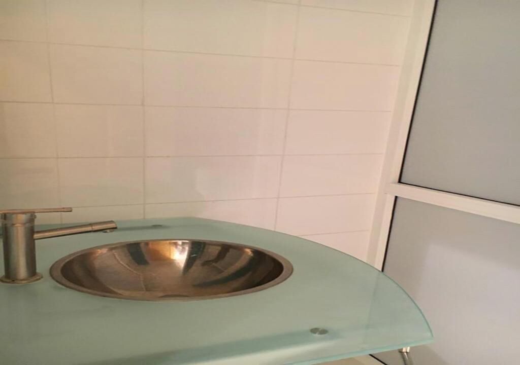 Un baño con lavamanos de acero inoxidable y encimera azul claro.