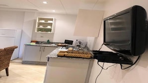 A compact kitchen with a built-in microwave, a small island with a sink, and a TV mounted on the wall. - Beautiful apartment in Saidia 4895 (Saidia)