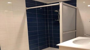 A bathroom with a shower area featuring blue tiles, a white sink, and a white toilet. - Beautiful apartment in Saidia 4895 (Saidia)
