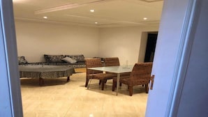 A dining area with a marble floor, a table, and wicker chairs. - Beautiful apartment in Saidia 4895 (Saidia)