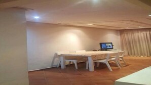 A room with a dining table, chairs, a television, and a curtain.