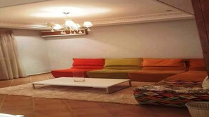 A living room with a sofa, a coffee table, and a chandelier.