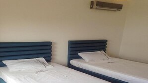 Two single beds with blue headboards in a room with a white wall and an air conditioning unit above. - Superb Villa in Marina Saidia 4899 (Saidia)
