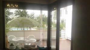 Une pièce dotée d’une porte vitrée donnant sur un espace extérieur avec une piscine et des chaises.