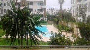 Un quartier résidentiel avec des immeubles d’appartements modernes, une piscine et de nombreux espaces verts.