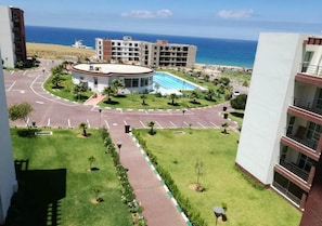 A hotel with a circular pool, a parking lot, and a view of the ocean.