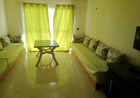 A living room with a sofa set, a table, and a television. - Apartment with a side view of the Atlantic Ocean 4911 (Asilah)