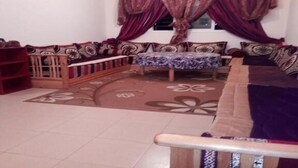 A living room with a sofa set, a small table, and a bookshelf. - Beautiful apartment in Les Jardins d'Ifrane 4930 (Ifrane)