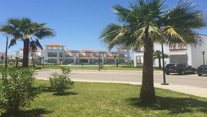Un edificio con fachada blanca y tejado de tejas rojas, rodeado de palmeras y un cielo azul despejado.