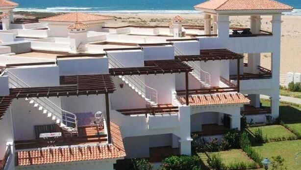 Un edificio de varios pisos con balcones, vista al mar y un área exterior techada.