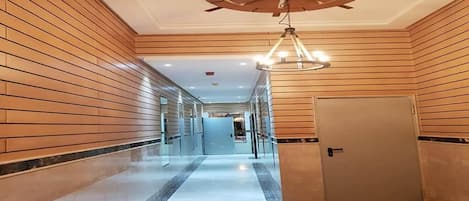 A hallway with wooden paneling, a ceiling fan, and a chandelier.