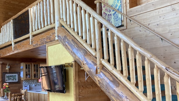 A wooden interior with a staircase, a dining area, and a kitchen. - Cozy, Quiet Small Town Log Home. With Beautiful Mountain View. (collbran colarado)