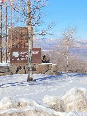 Une enseigne indiquant l’emplacement de la station de ski de Powell Mountain, avec en arrière-plan un paysage enneigé et des montagnes.