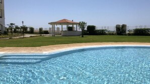 Une piscine à l’eau d’un bleu limpide, entourée d’une pelouse bien entretenue et agrémentée d’un kiosque.