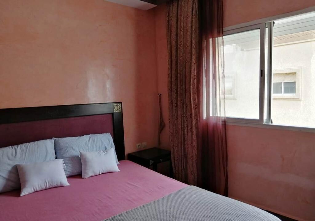 A bedroom with a bed, a nightstand, and a window with curtains.