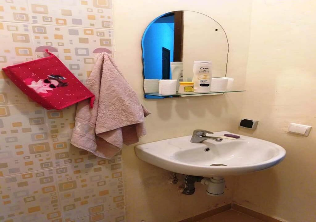 Ein Badezimmer mit einem weißen Waschbecken, einem Spiegel und einem Handtuchhalter mit einem pinken Handtuch.
