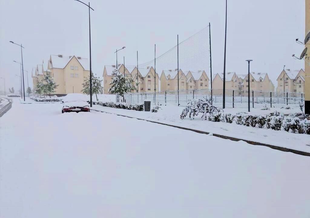 A residential street with snow-covered houses and a clear sky.