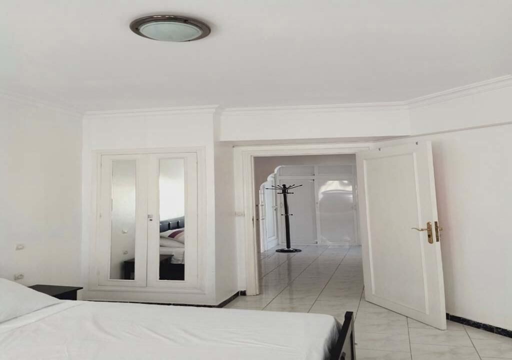 Ein Hotelzimmer mit Bett, einem Schrank und einer Tür zu einem anderen Raum.