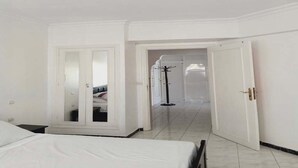 Una camera d'albergo con un letto, un armadio e una porta che dà su un'altra stanza.