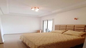 Ein Schlafzimmer mit einem großen Bett, einer Deckenleuchte und einer Tür zu einem anderen Raum.