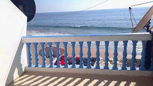 Un balcón con vista al mar, una antena parabólica y un objeto rojo en el suelo.