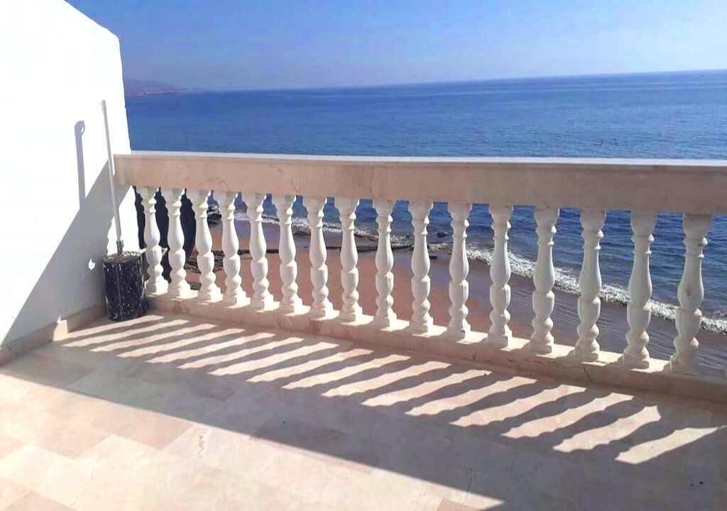 Un balcón con barandilla blanca que da al mar.
