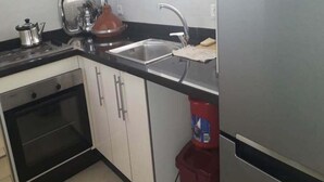 A kitchen with a stainless steel sink, a kettle, and a red container. - Superb seafront apartment in Taghazout 4965 (Taghazout)