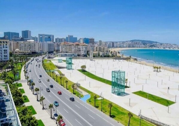 A coastal cityscape with a wide road, beachfront promenade, and modern buildings. - Beautiful apartment in Tangier 4969 (Tanger)