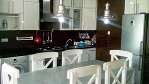 A modern kitchen with white cabinets, a stainless steel stove, and a dining area with white chairs. - Superb sea view apartment in Fakhama 4970 (Tanger)