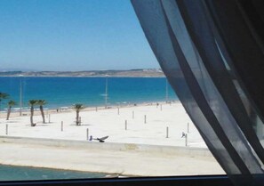 A beach with a clear view of the sea and distant land.
