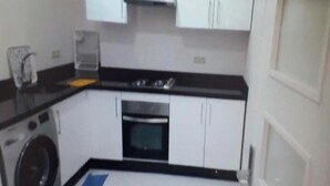 A compact kitchen with a washing machine, a stove, and a microwave. - Superb apartment in Le Printemps 4972 (Tanger)