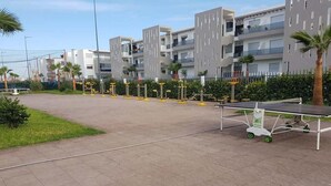 A residential area with modern apartment buildings, a sports court, and a small kiosk.